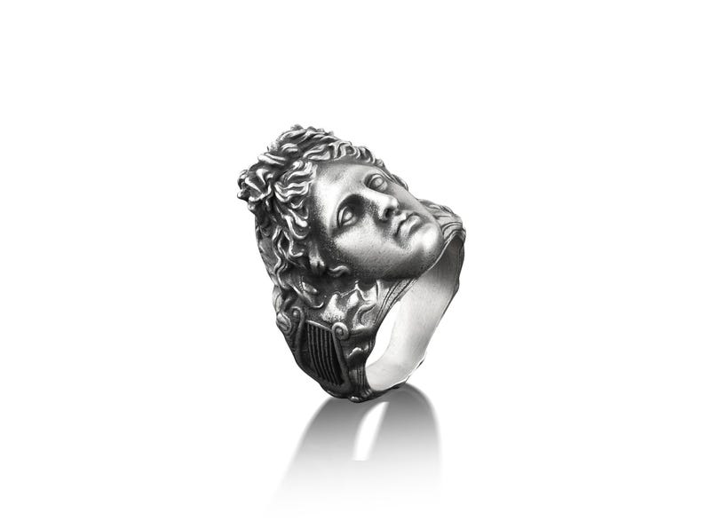 Peut inclure: Une bague en argent avec un visage sculpt&eacute; d&eacute;taill&eacute; d'une personne avec une couronne de feuilles.
