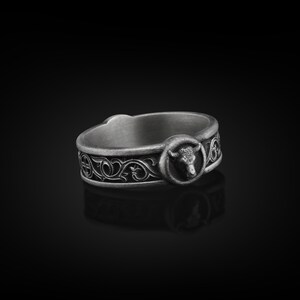May include: A silver ring with an intricate design featuring a bull's head and floral motifs.