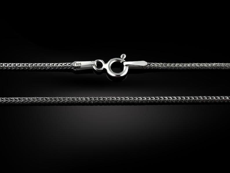 May include: A silver chain necklace with a lobster clasp. The chain is made of a braided design and is marked with "925" for sterling silver.