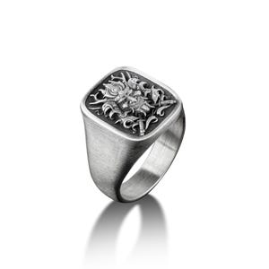 May include: A silver signet ring with a square face featuring a detailed engraved design of a mythical creature with wings and a crown.