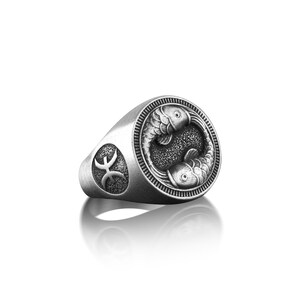 Peut inclure: Bague en argent avec un motif d&eacute;taill&eacute; de deux poissons entrelac&eacute;s, symbolisant le signe du zodiaque des Poissons. La bague pr&eacute;sente &eacute;galement le symbole des Poissons sur le c&ocirc;t&eacute;.