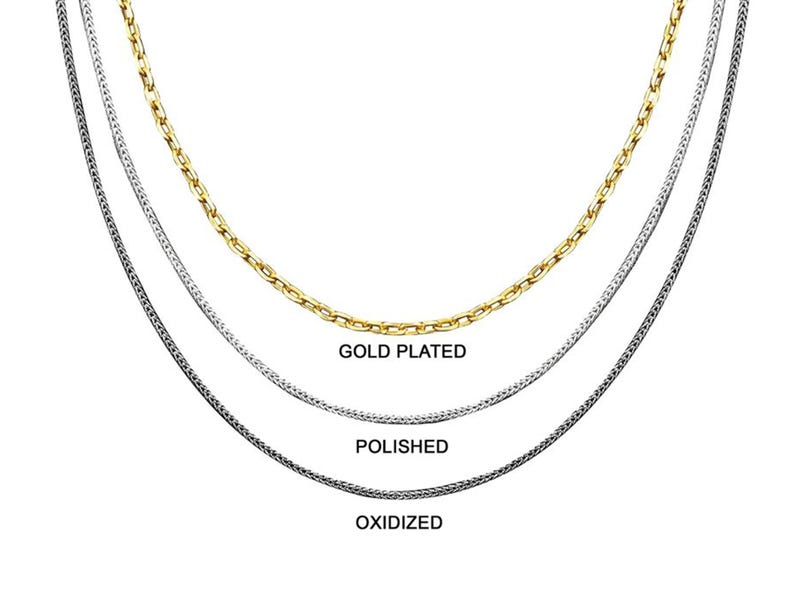 May include: Three silver chains, one gold plated, one polished, and one oxidized. The chains are layered on top of each other.