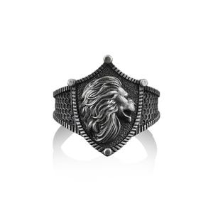 May include: A silver ring with a shield design featuring a lion's head in profile. The shield is surrounded by a textured band.
