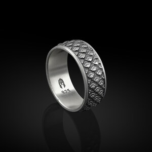 K&ouml;nnte beinhalten: Ein silberner Ring mit einem strukturierten Muster auf der Band. Der Ring ist mit "925" und einem kleinen Bild eines Helms gekennzeichnet.
