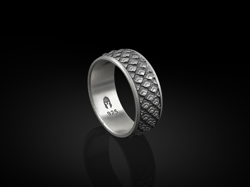 K&ouml;nnte beinhalten: Ein silberner Ring mit einem strukturierten Muster auf der Band. Der Ring ist mit "925" und einem kleinen Bild eines Helms gekennzeichnet.