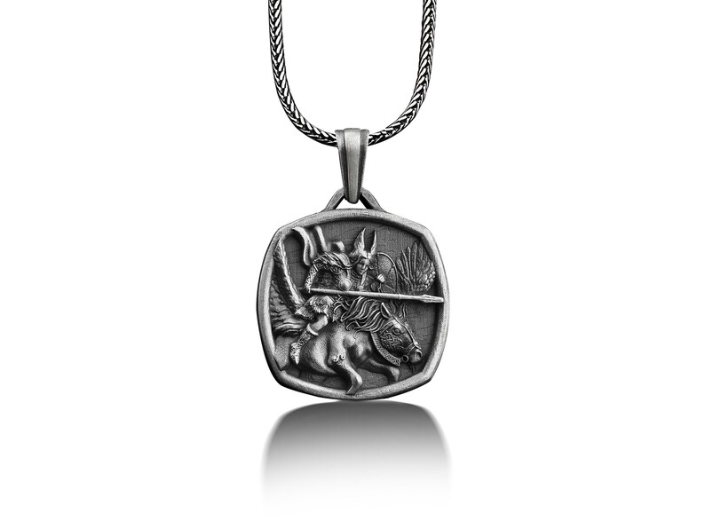 May include: Silver pendant necklace featuring a detailed depiction of a winged warrior riding a horse, holding a spear. The pendant is square shaped with rounded corners.