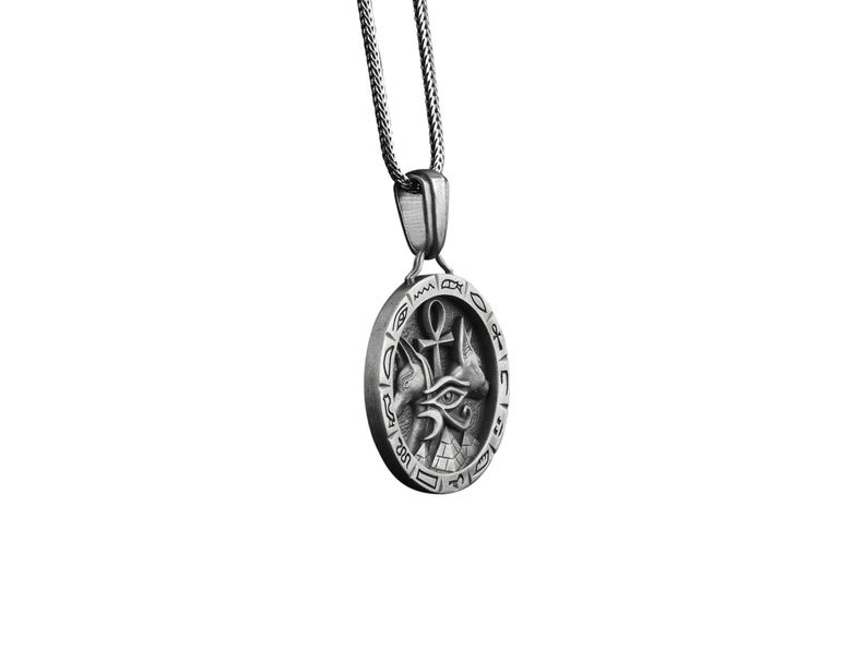 Pu&ograve; includere: Collana con ciondolo in argento con un occhio di Horus egizio, un ankh e altri simboli in un design circolare.