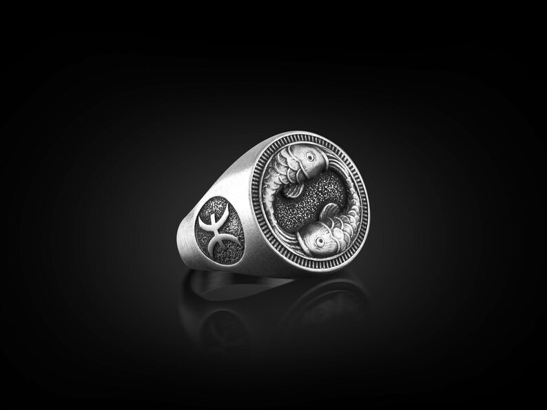Peut inclure: Une bague en argent avec un motif d&eacute;taill&eacute; de deux poissons entrelac&eacute;s, symbolisant le signe du zodiaque des Poissons. La bague pr&eacute;sente &eacute;galement le symbole des Poissons sur le c&ocirc;t&eacute;.
