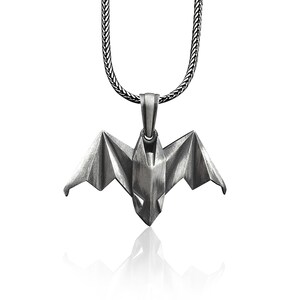 May include: A silver chain necklace with a silver origami bat pendant.