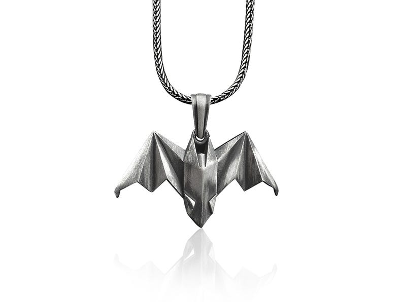 May include: A silver chain necklace with a silver origami bat pendant.