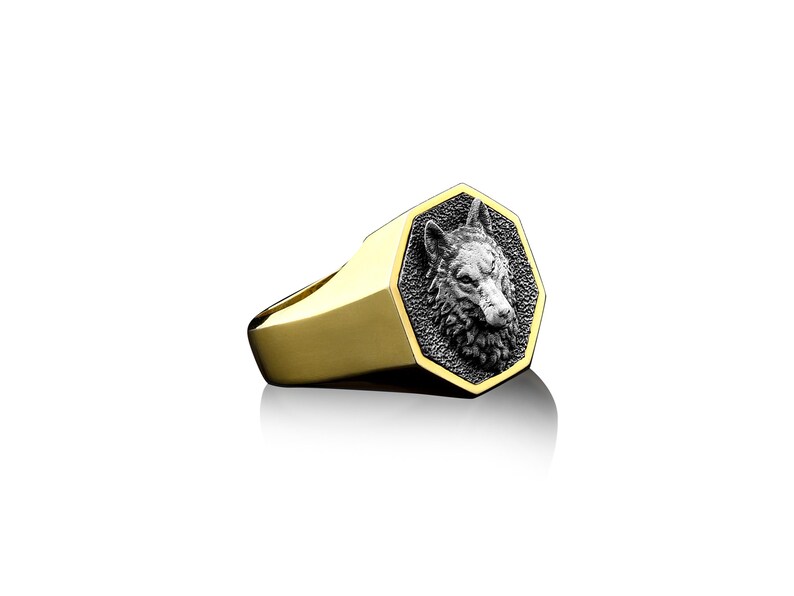 May include: A gold ring with a silver wolf head design. The wolf head is in a hexagonal shape and is detailed with a textured finish.