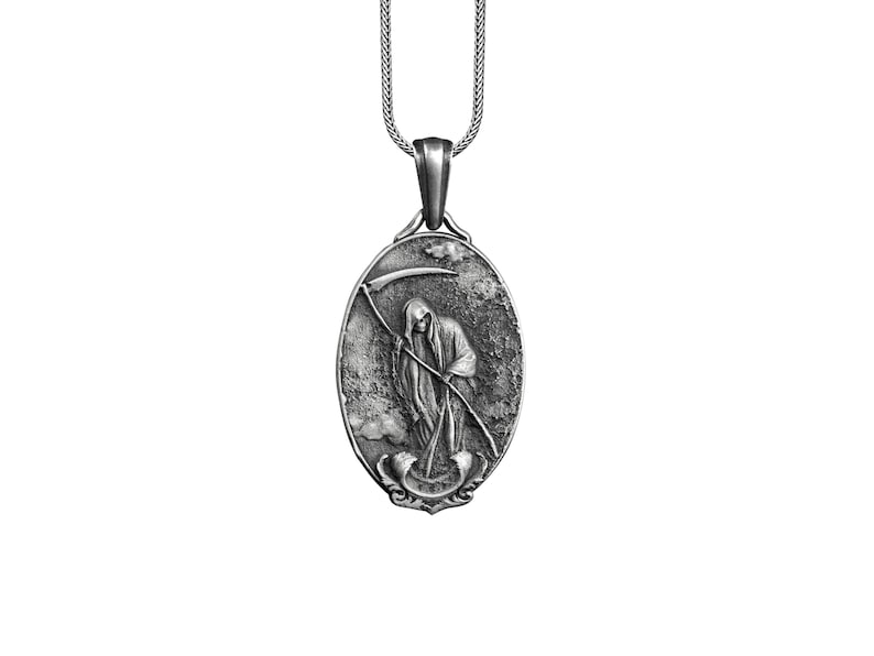 Puede incluir: Un collar con un colgante de plata que presenta una representaci&oacute;n detallada de la Muerte sosteniendo una guada&ntilde;a. El colgante tiene forma ovalada y tiene un aspecto texturizado y envejecido.
