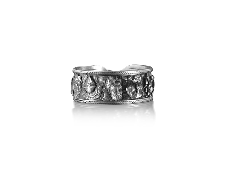 Pu&ograve; includere: Un anello d'argento con un design intricato di fiori e foglie. L'anello &egrave; largo e ha una superficie testurizzata.