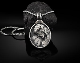 Puede incluir: Un collar con un colgante de plata con una imagen detallada de Jesús con una corona de espinas. El colgante es de forma ovalada y tiene un fondo texturizado con rayos de luz que emanan del centro. El collar está sobre un fondo negro.