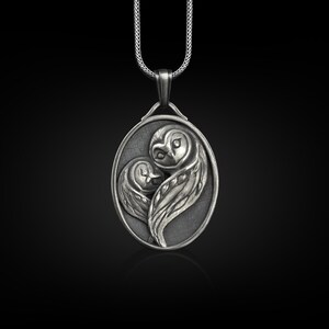 May include: Silver pendant necklace featuring two owls in a heart shape. The owls are intricately detailed and have a realistic appearance.