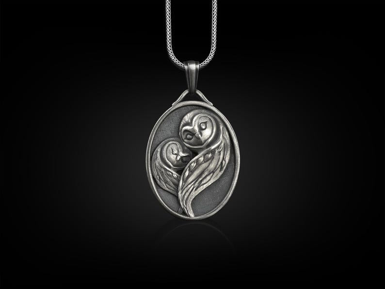 May include: Silver pendant necklace featuring two owls in a heart shape. The owls are intricately detailed and have a realistic appearance.