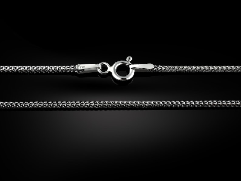 May include: A silver chain necklace with a lobster clasp. The chain is made of a braided design and is marked with "925" for sterling silver.