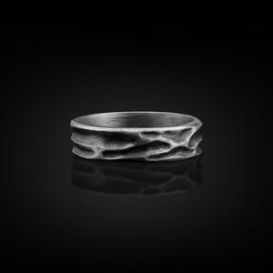 May include: A silver ring with a textured, organic pattern. The ring is wide and has a matte finish.