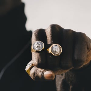 May include: Two gold rings with octagonal settings. The rings feature a gorilla and a wolf head design.