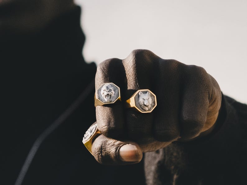May include: Two gold rings with octagonal settings. The rings feature a gorilla and a wolf head design.