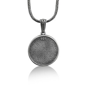 May include: A silver pendant necklace with a textured, circular pendant. The pendant is marked with "925" and hangs from a woven chain. The necklace is displayed against a white background.