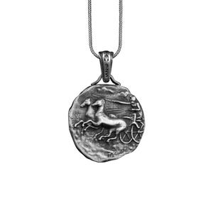 May include: Silver pendant necklace featuring a round coin with a detailed relief sculpture of a chariot pulled by two horses. The coin has a textured surface and a raised rim.
