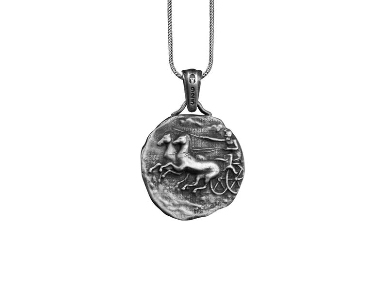 May include: Silver pendant necklace featuring a round coin with a detailed relief sculpture of a chariot pulled by two horses. The coin has a textured surface and a raised rim.