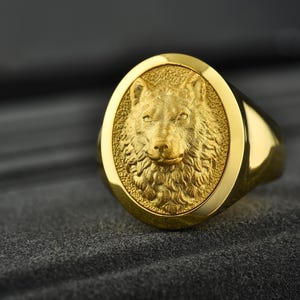 May include: A gold ring with a detailed wolf head design. The wolf's head is raised and has a textured fur pattern.