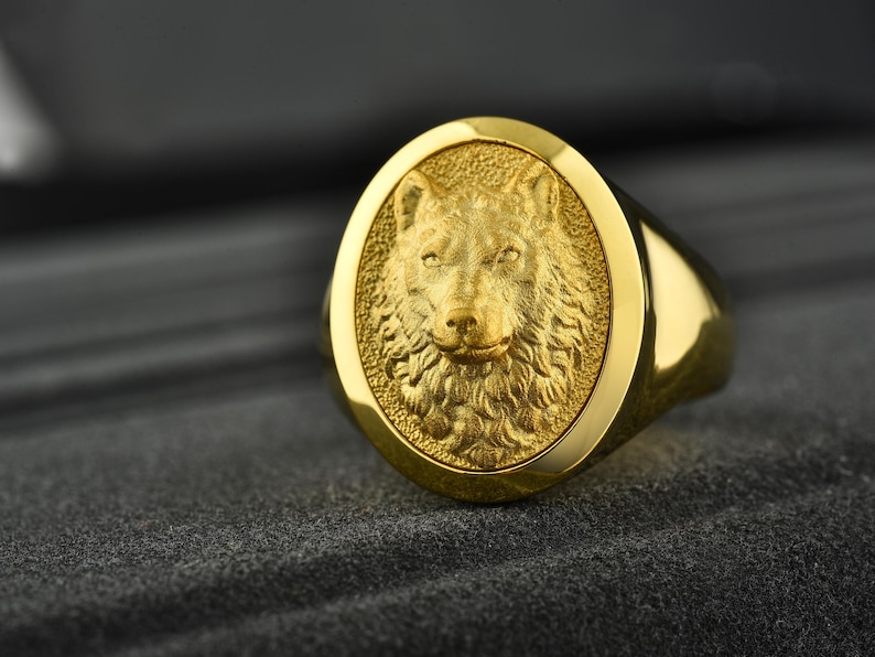 May include: A gold ring with a detailed wolf head design. The wolf's head is raised and has a textured fur pattern.