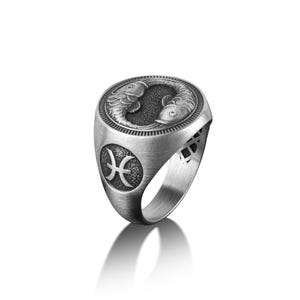 Peut inclure: Une bague en argent avec une gravure d&eacute;taill&eacute;e de deux poissons et le symbole astrologique des Poissons.