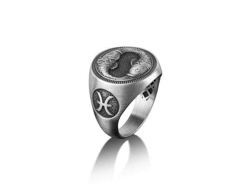 Peut inclure: Une bague en argent avec une gravure d&eacute;taill&eacute;e de deux poissons et le symbole astrologique des Poissons.
