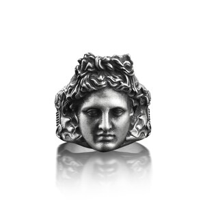 Peut inclure: Une bague en argent avec un visage sculpt&eacute; d&eacute;taill&eacute; d'une personne aux cheveux longs. La bague est une pi&egrave;ce forte au design classique.