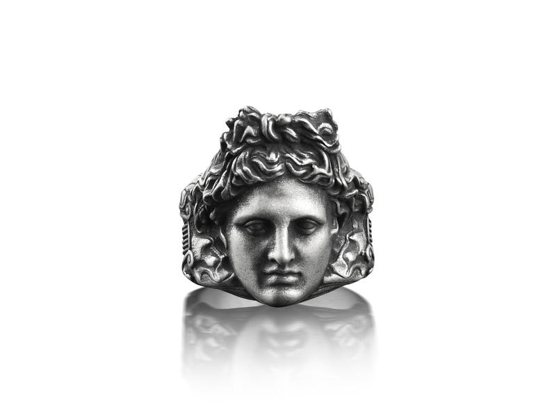 Peut inclure: Une bague en argent avec un visage sculpt&eacute; d&eacute;taill&eacute; d'une personne aux cheveux longs. La bague est une pi&egrave;ce forte au design classique.
