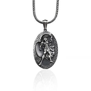 May include: Silver chain necklace with an oval pendant featuring a detailed relief of a warrior holding a spear and shield.