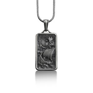 May include: A silver pendant necklace with a rectangular tag featuring a detailed engraving of a mythical sea god holding a trident and steering a ship.