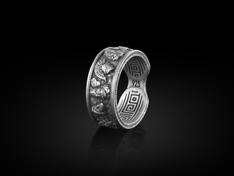 Pu&ograve; includere: Un anello d'argento con un design intricato che presenta un motivo a chiave greca e il numero 925.