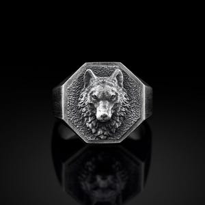 May include: A silver ring with an octagonal face featuring a detailed wolf head design.