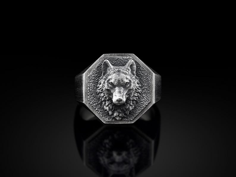 May include: A silver ring with an octagonal face featuring a detailed wolf head design.