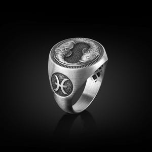 Peut inclure: Une bague en argent avec un motif d&eacute;taill&eacute; de deux poissons et le symbole astrologique des Poissons.
