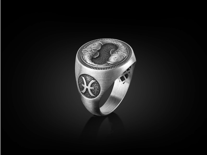 Peut inclure: Une bague en argent avec un motif d&eacute;taill&eacute; de deux poissons et le symbole astrologique des Poissons.