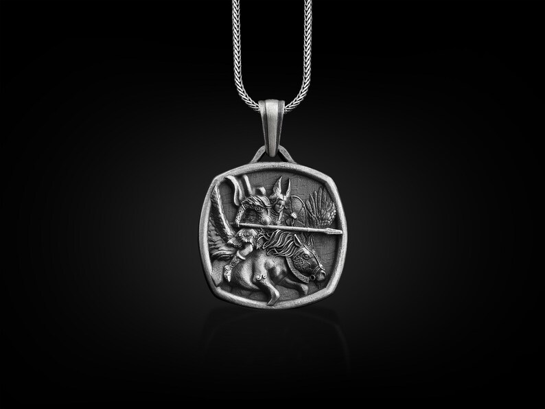May include: A silver pendant necklace featuring a detailed depiction of a winged creature riding a horse, holding a spear. The pendant is square shaped with a beveled edge.