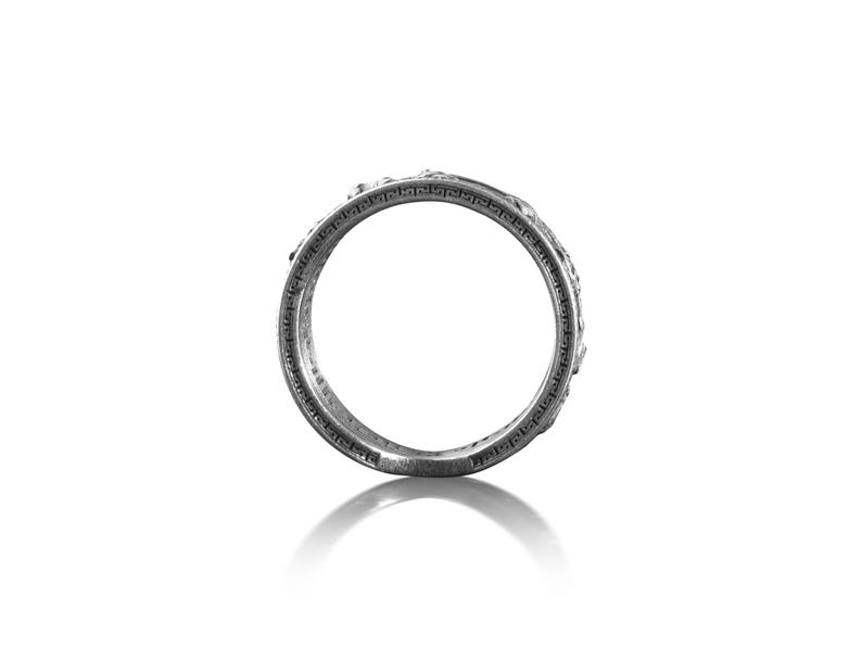 Pu&ograve; includere: Un anello d'argento con un design intricato attorno alla fascia.