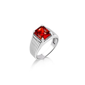 May include: A silver ring with a red square-shaped gemstone. The ring has a textured band with parallel lines.