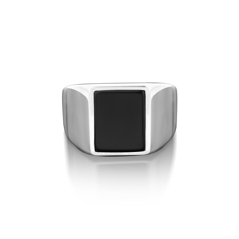 May include: A silver ring with a black rectangular stone.