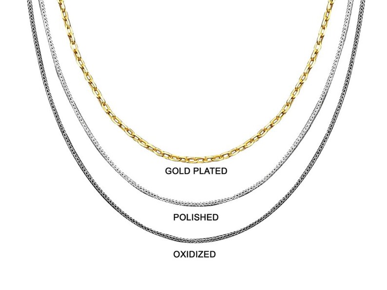 May include: Three silver chains, one gold plated, one polished, and one oxidized. The chains are layered on top of each other.