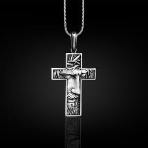 May include: A silver pendant necklace featuring a detailed cross with a depiction of Jesus' face within the cross.