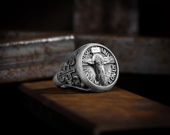 May include: A silver ring with a detailed design featuring a cross and a depiction of Jesus Christ on the cross. The ring has the words "Jesus Christ Have Mercy On Us" inscribed around the image.
