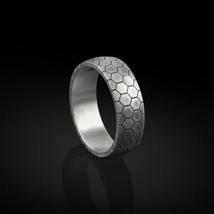 May include: A silver ring with a hexagonal pattern on the band.