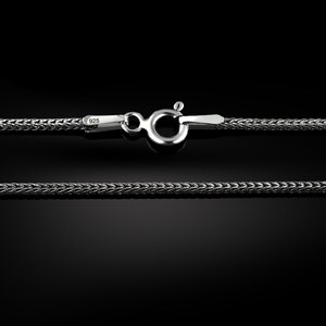 May include: A silver chain necklace with a lobster clasp. The chain is made of a woven pattern and is marked with "925".