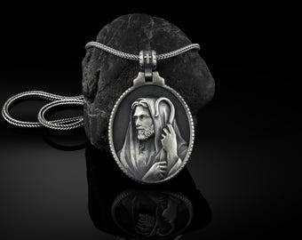Puede incluir: Collar con colgante de plata con un relieve detallado de Jesucristo con un cayado de pastor. El colgante es redondo y tiene un fondo negro.